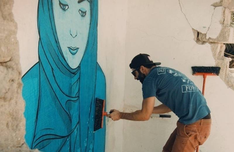 Umělec dotváří malbu ve čtvrti Satwa